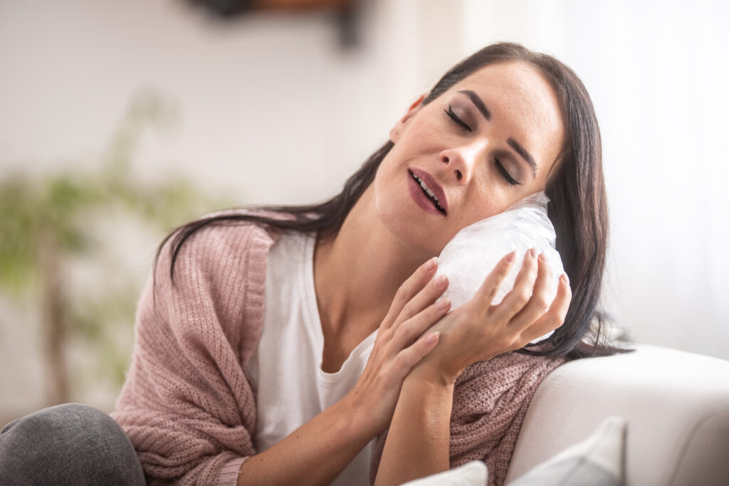 Woman pressing an ice pack to her jaw for dental pain or emergency treatment