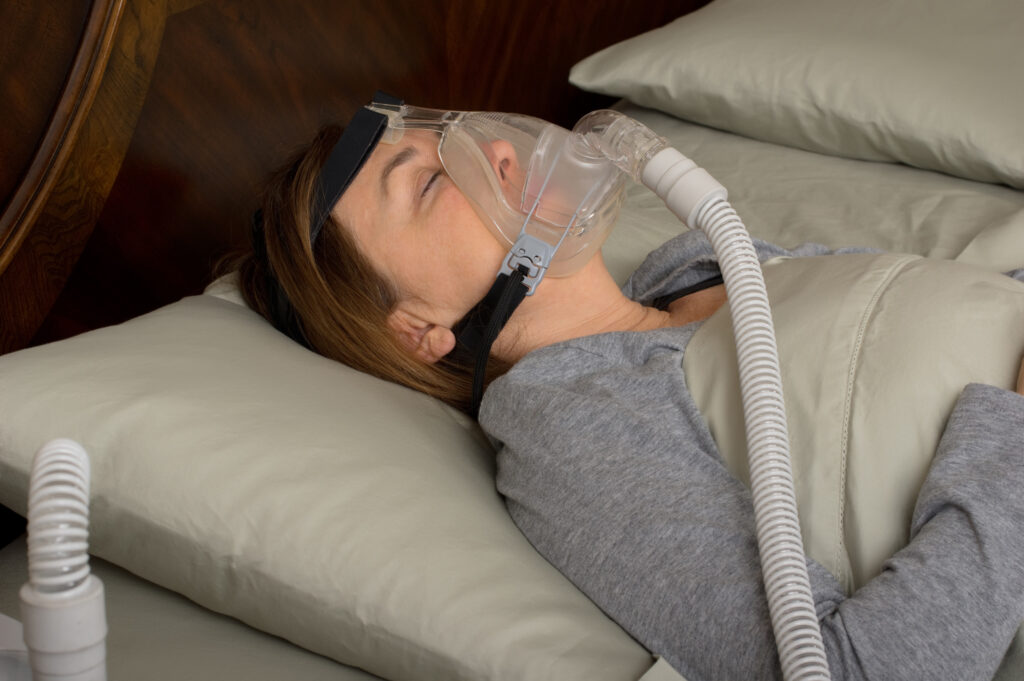 Woman sleeping peacefully using a CPAP machine for sleep apnea treatment Woman sleeping peacefully using a CPAP machine for sleep apnea treatment